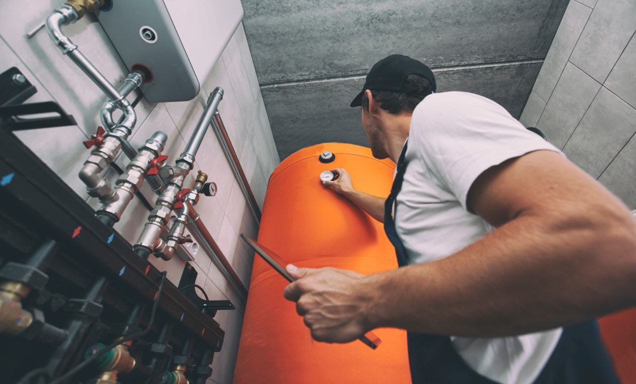Technician checking the pressure on a boiler or furnace in the basement of a building